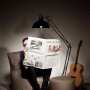 Sitting Point Sessel Swing Anthrazit mit Hocker, Mann liest Zeitung unter Lampe.