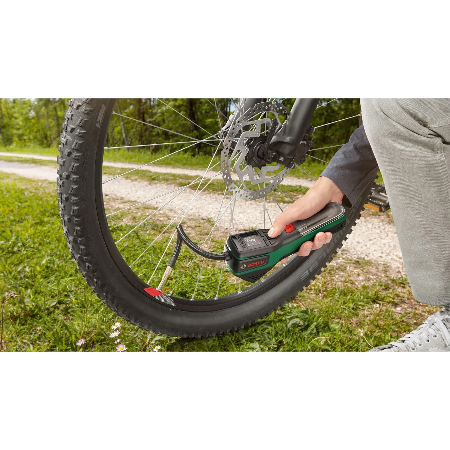 Bosch Pneo Akku-Druckluftpumpe beim Aufpumpen eines Fahrradreifens im Freien.