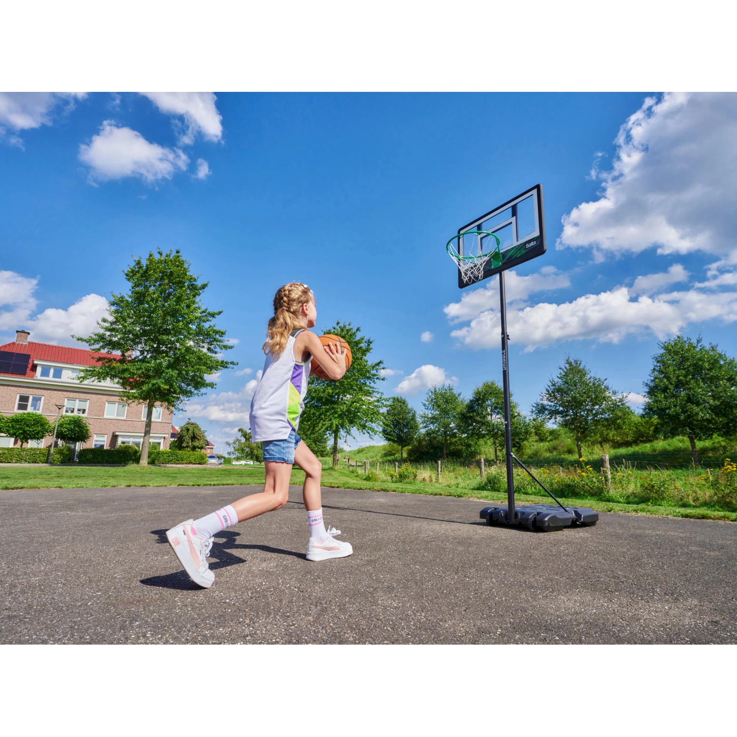 Mädchen beim Basketballspielen mit dem Salta Basketballständer Dribble im Garten.