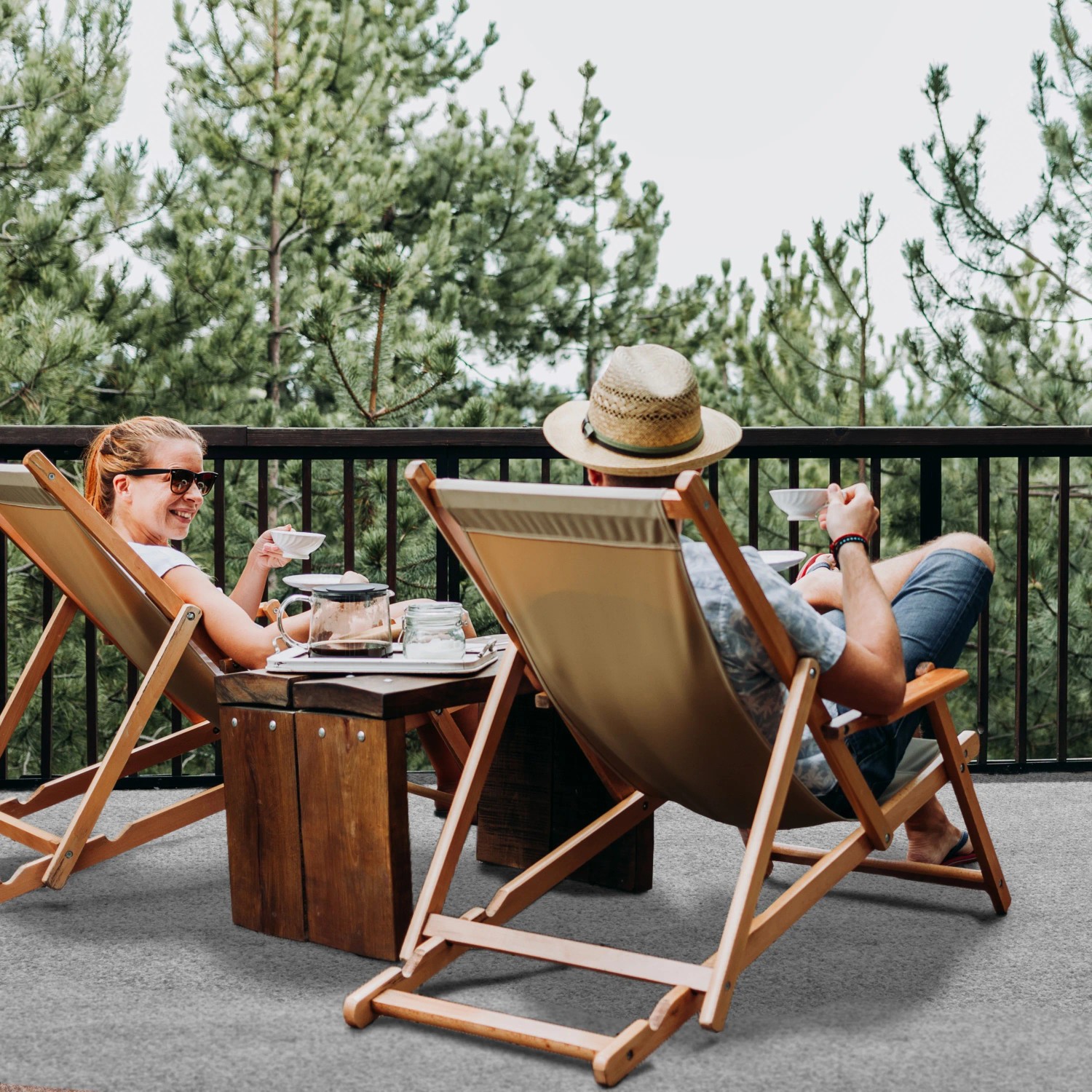 Grauer Primaflor Rasenteppich auf Terrasse mit entspannten Personen in Liegestühlen.