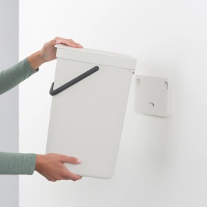 Brabantia Abfallbehälter Sort & Go, 16 l, Grau, mit Wandhalterung in der Hand gehalten.