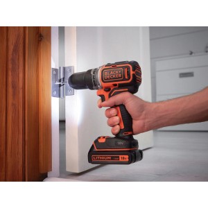 Black+Decker Akku-Bohrschrauber beim Schrauben an einer Tür, 18V, mit LED-Licht.