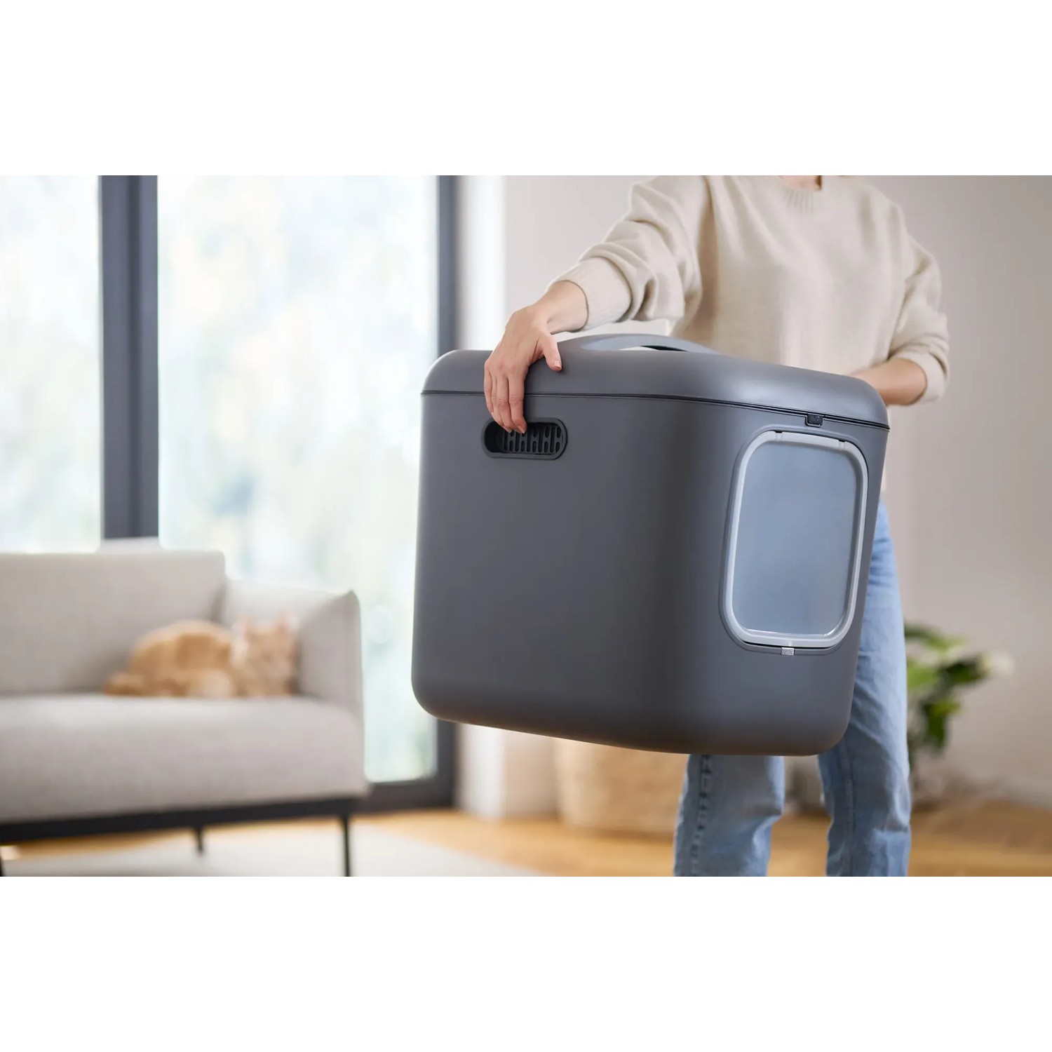 Anthrazitfarbene Rotho Katzentoilette Biala XL mit Tür und Griffen, getragen von einer Person.