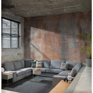 Wohnraum mit Fototapete Rasch Factory V in Rotbraun mit Rost-Optik hinter grauer Couch.