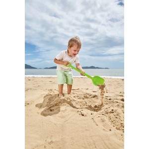 Kind spielt am Strand mit grüner Hape Starke Schaufel (40 cm) im Sand.