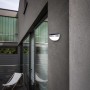 Lutec Solar-Außenwandleuchte Bubble aus Edelstahl an grauer Hauswand. Moderne Solar-Wandlampe.