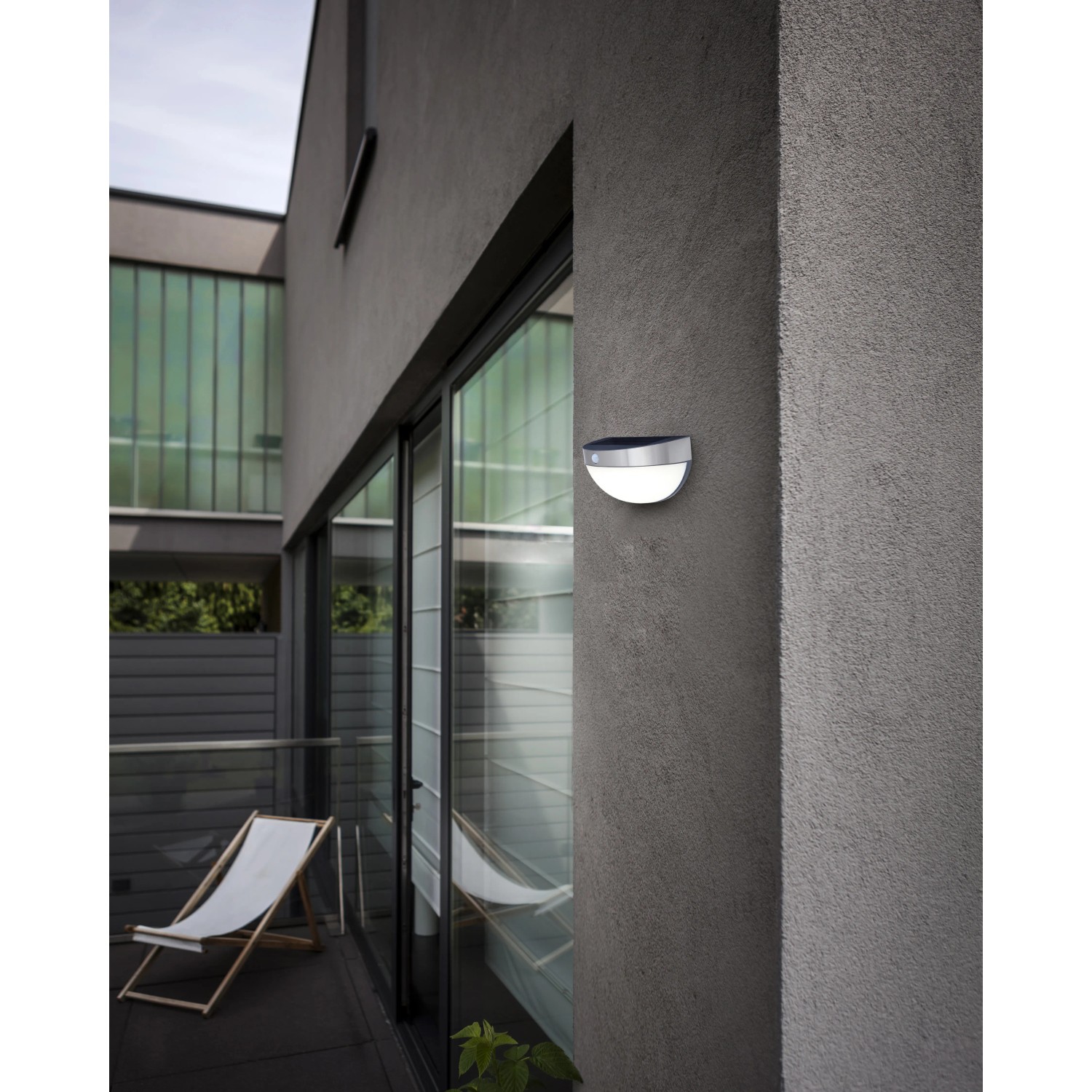 Lutec Solar-Außenwandleuchte Bubble aus Edelstahl an grauer Hauswand. Moderne Solar-Wandlampe.