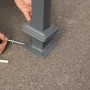 Detailaufnahme: Montage der Westmann Mülltonnenverkleidung Planum Metall. Bodenbefestigung.
