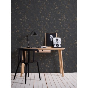 A.S. Création Vliestapete Trendwall Putz Used Schwarz-Gold im Raum mit Schreibtisch und Stuhl.