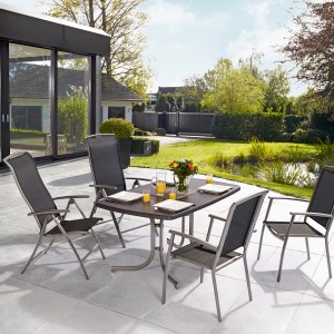 Rechteckiger, grauer Gartentisch Vigo Sevelit (150x90cm) mit vier Stühlen im Garten.