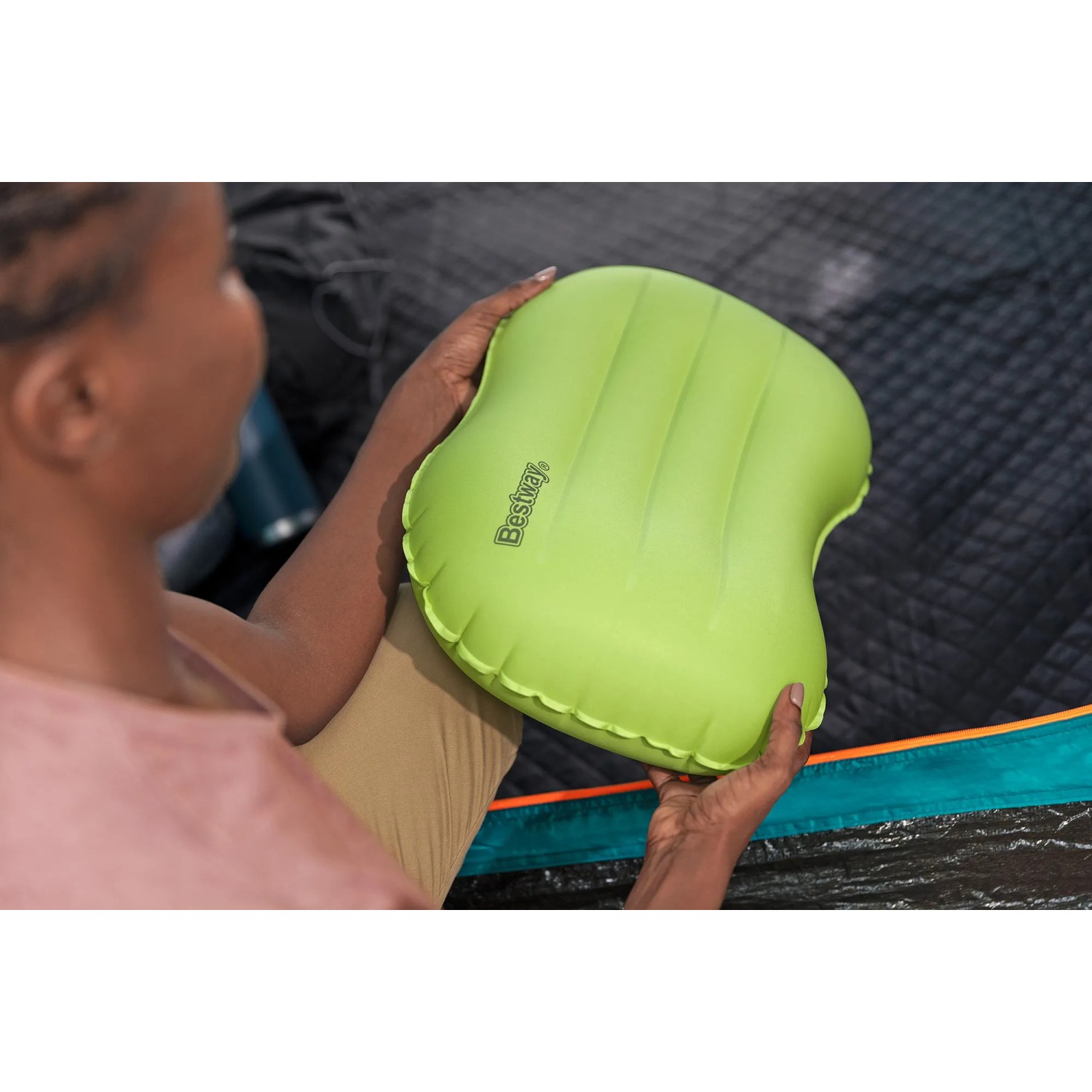Grünes Bestway Air Pillow Wanderlite Camping-Kissen, gehalten in Händen vor Zelt.