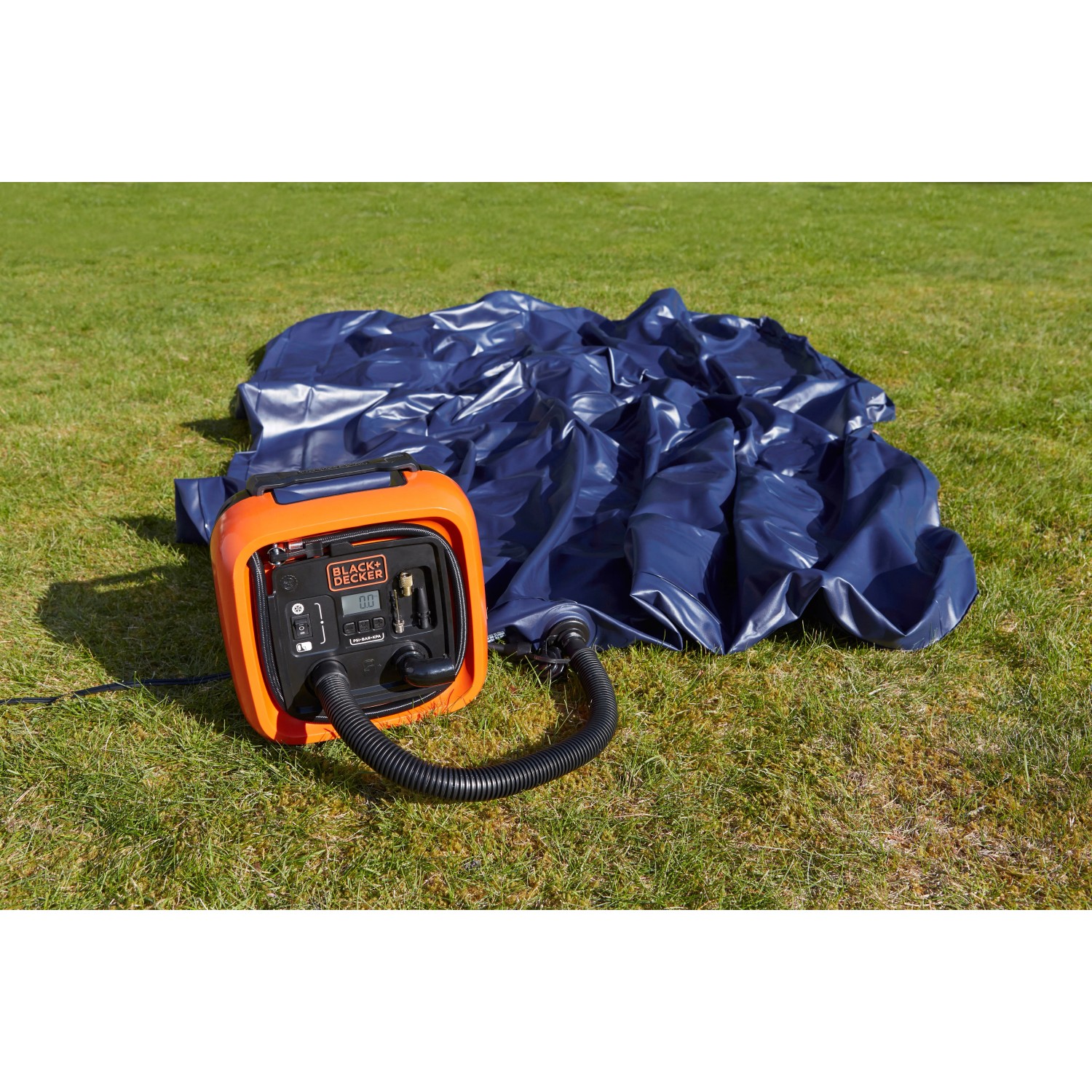 Black+Decker Luftpumpe ASI400 (12V) beim Aufpumpen einer blauen Luftmatratze auf Rasen.