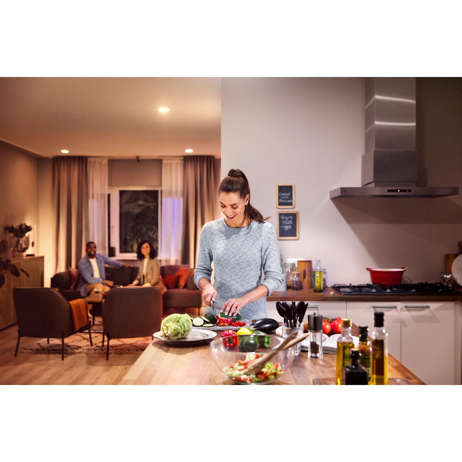 Szene mit Philips Hue E27 LED Glühbirnen, die eine Küche beleuchten, während eine Frau kocht.