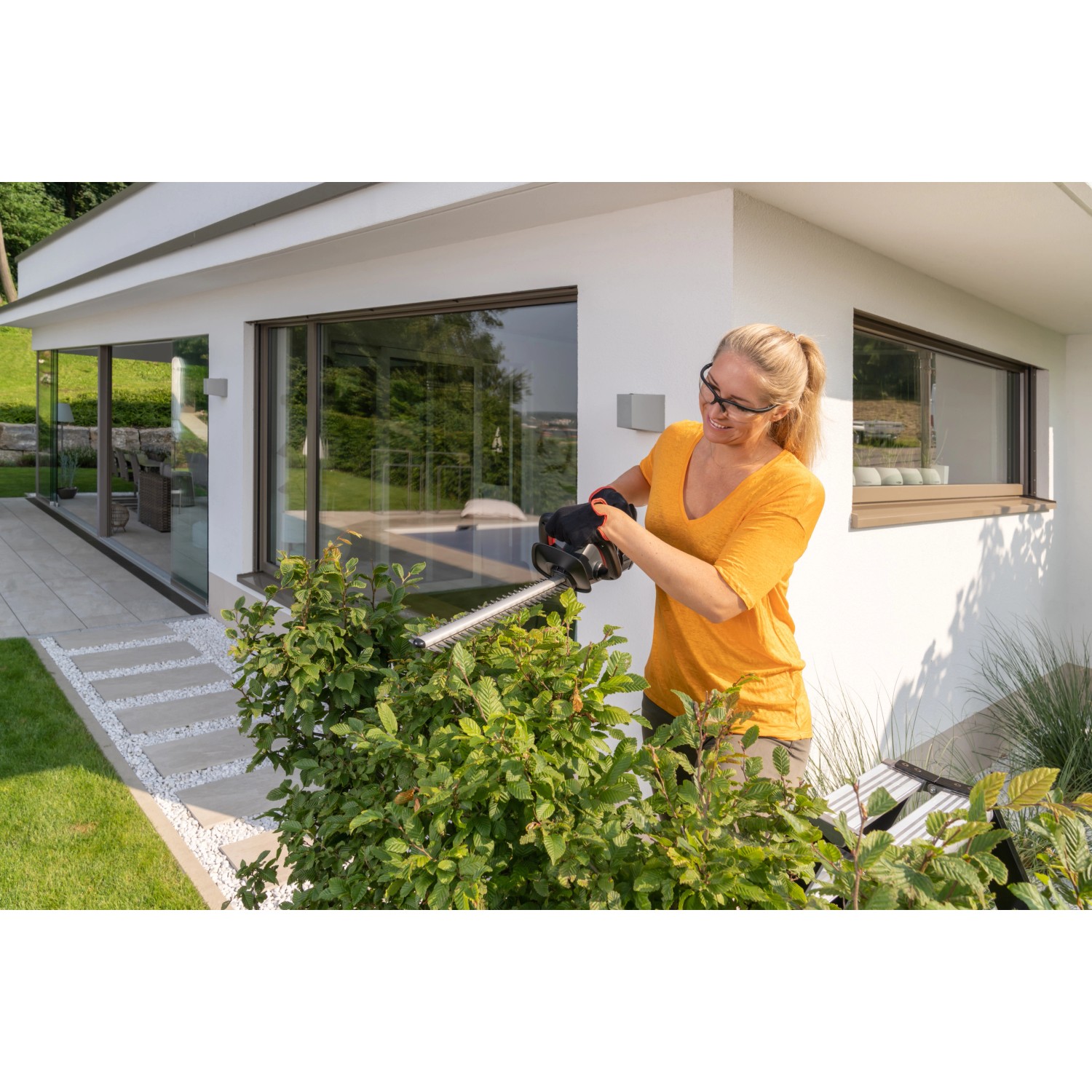 Frau schneidet Hecke mit Al-Ko Akku-Heckenschere HT 1845. Inklusive Akku, kompatibel mit Bosch.