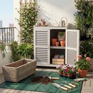 Grau-weißer Relaxdays Pflanztisch aus Tannenholz mit Eisen-Arbeitsplatte, Unterschrank, auf Balkon mit Gartenzubehör.