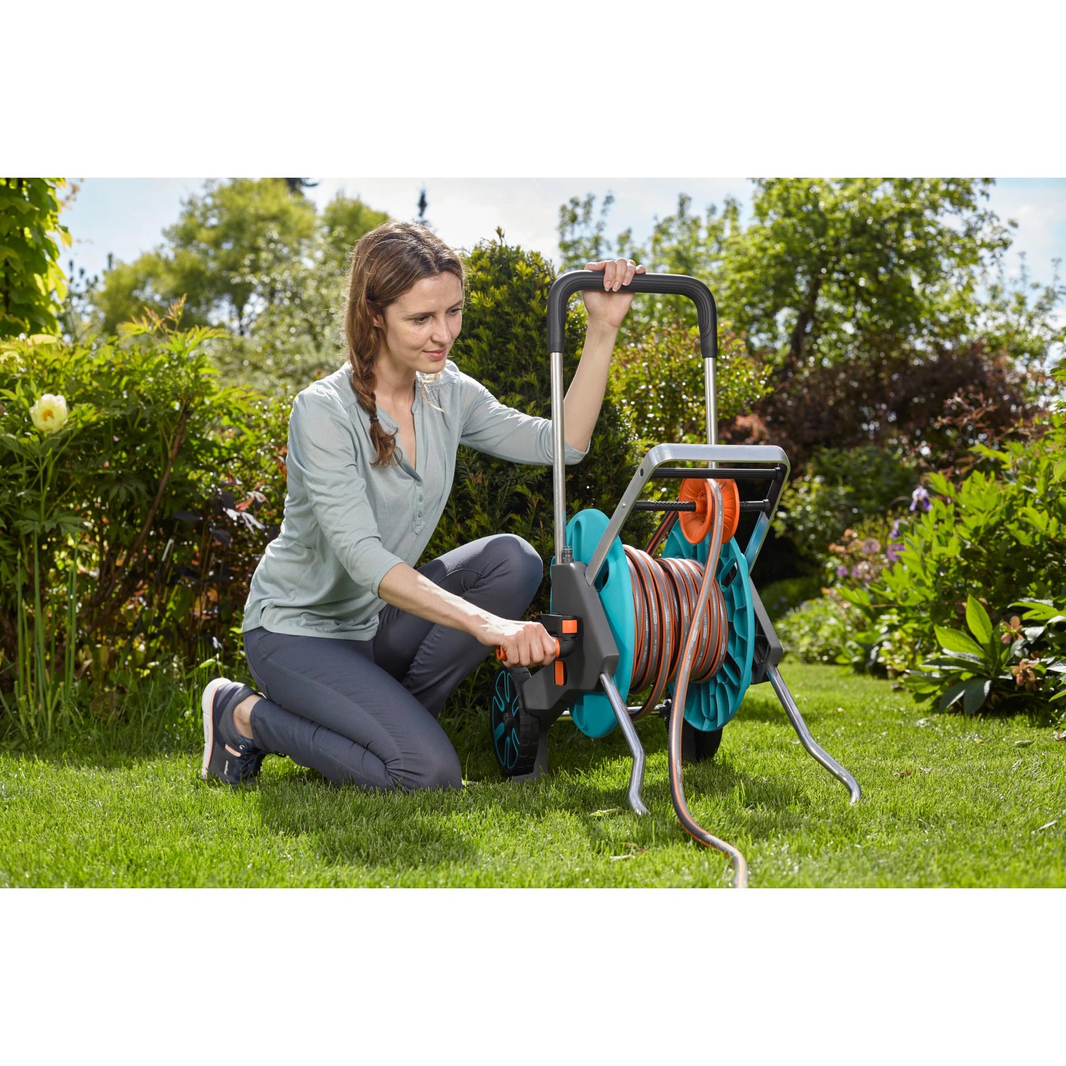 Frau bedient Gardena CleverRoll M Easy Schlauchwagen im Garten.