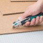 Hand schneidet Pappe mit wolfcraft Profi-Dual-Sicherheitsmesser (Trapezklinge).
