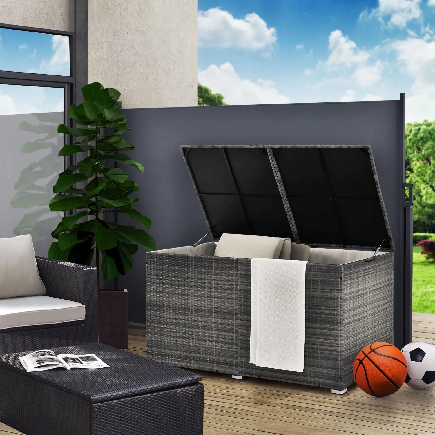 Grau melierte Polyrattan Auflagenbox Ikaria (950L) mit Innenplane für Gartenmöbel, geöffnet mit Kissen und Decke.