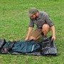 Mann baut Bestway Alpine Dome Zelt für 4 Personen auf grünem Rasen auf.