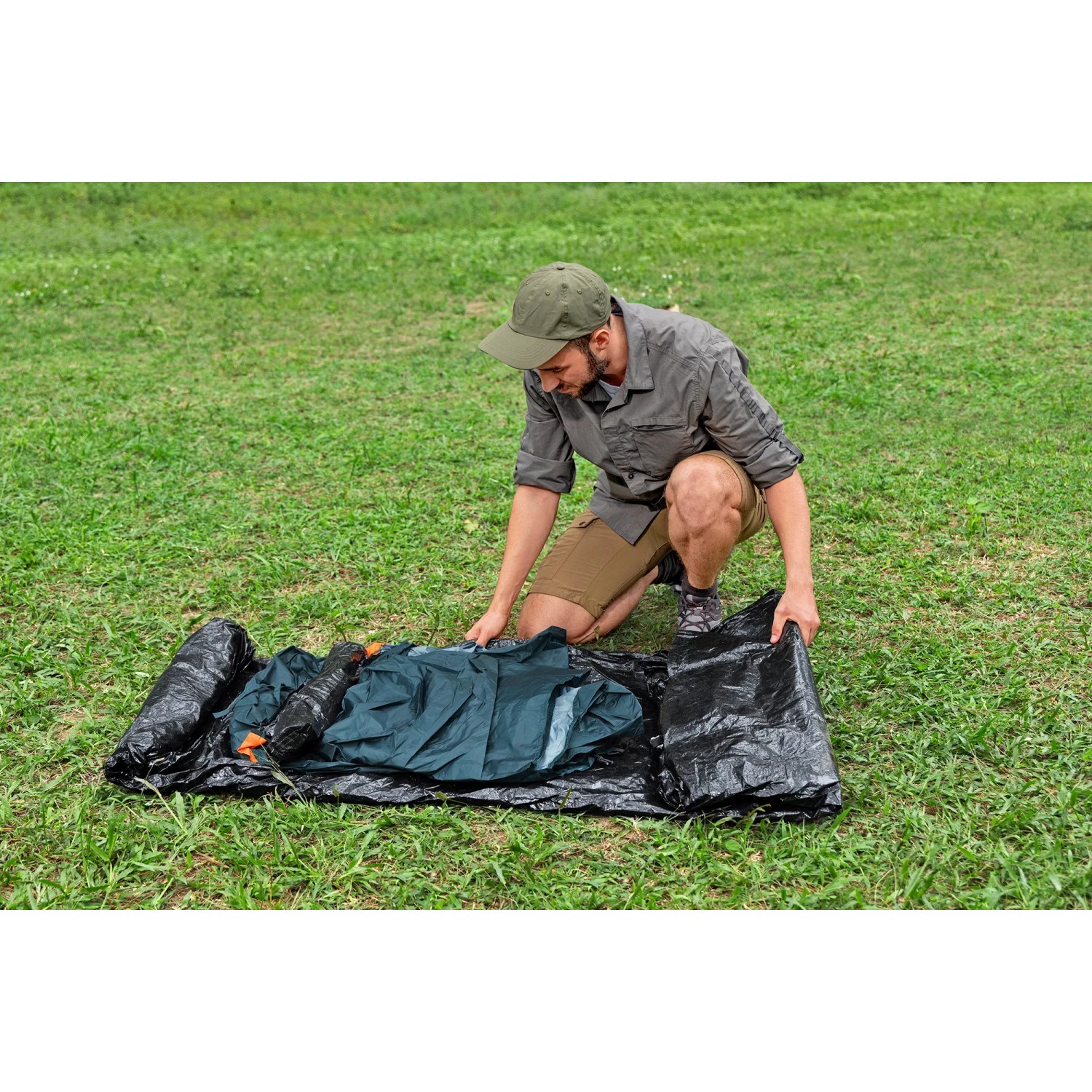 Mann baut Bestway Alpine Dome Zelt für 4 Personen auf grünem Rasen auf.