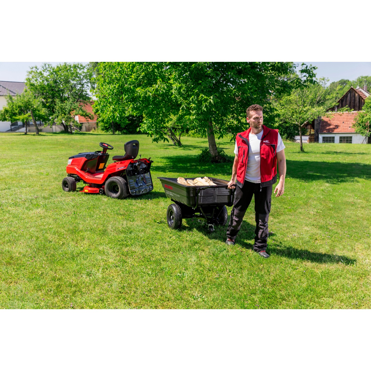 Al-Ko Combi Trailer CT 400 mit Rasentraktor und Person im Garten.