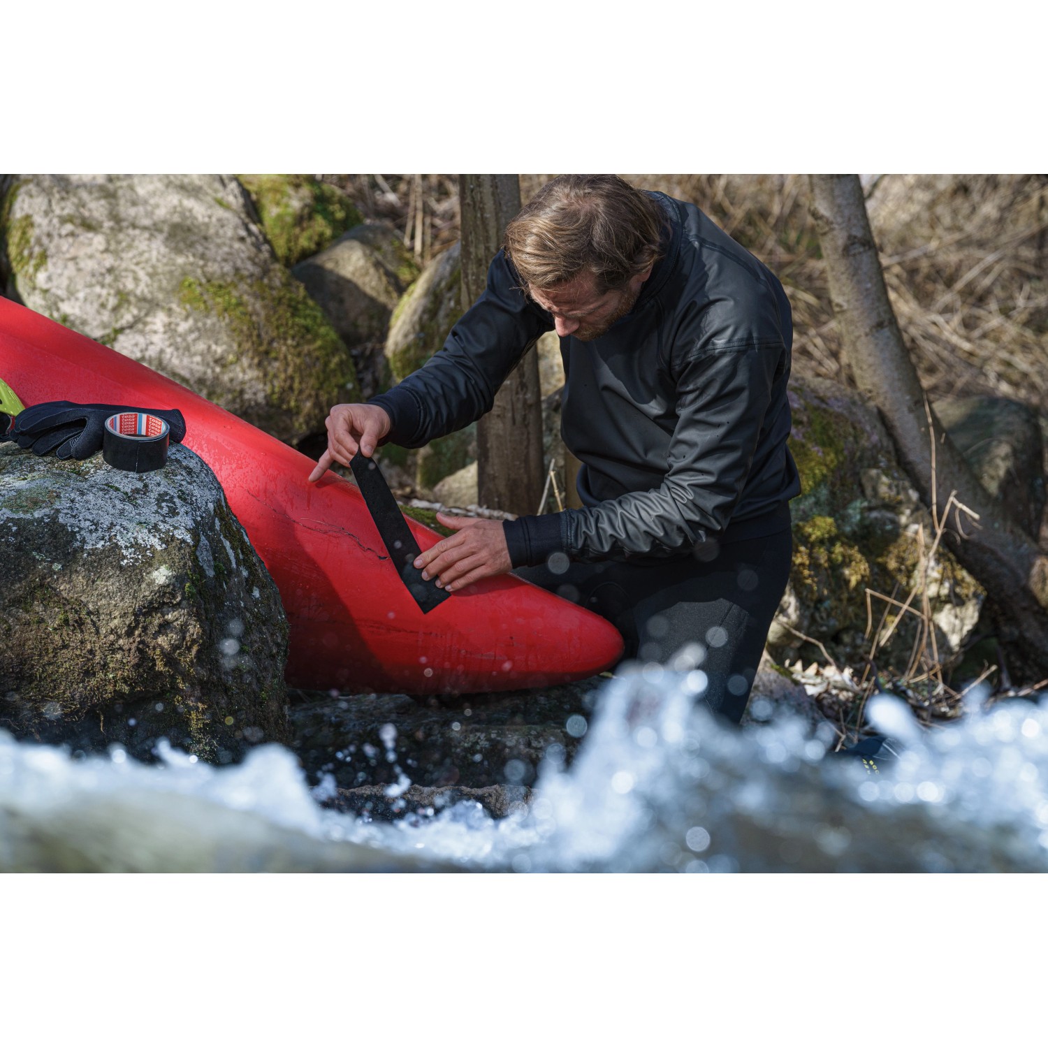 Mann repariert Kajak mit Tesa Reparaturband Ultra Power Under Water.