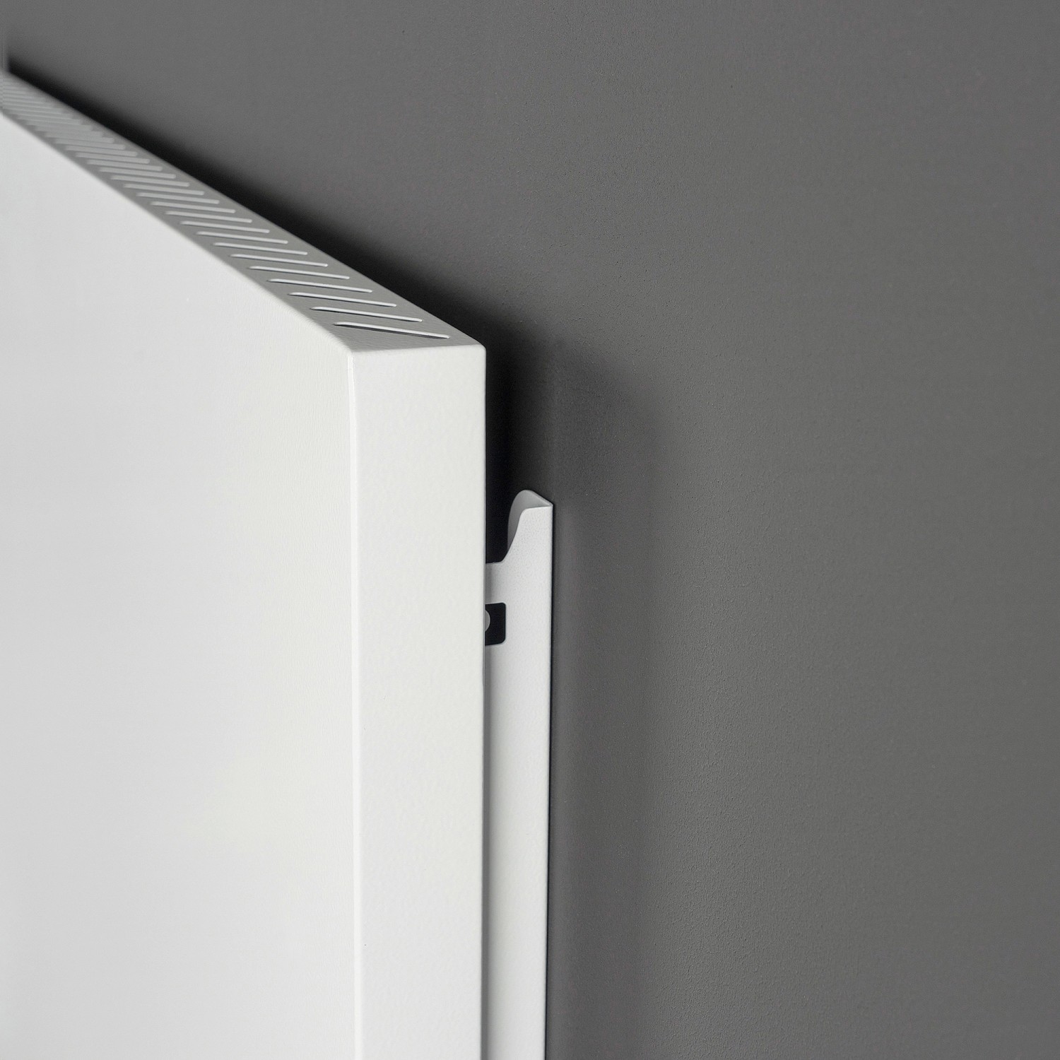 Weiße Vasner Hybrid-Infrarotheizung Konvi 900 W an grauer Wand, Detailaufnahme.