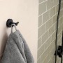 Tesa Moon Bademantelhaken in Graphit mit Handtuch an Wand montiert.