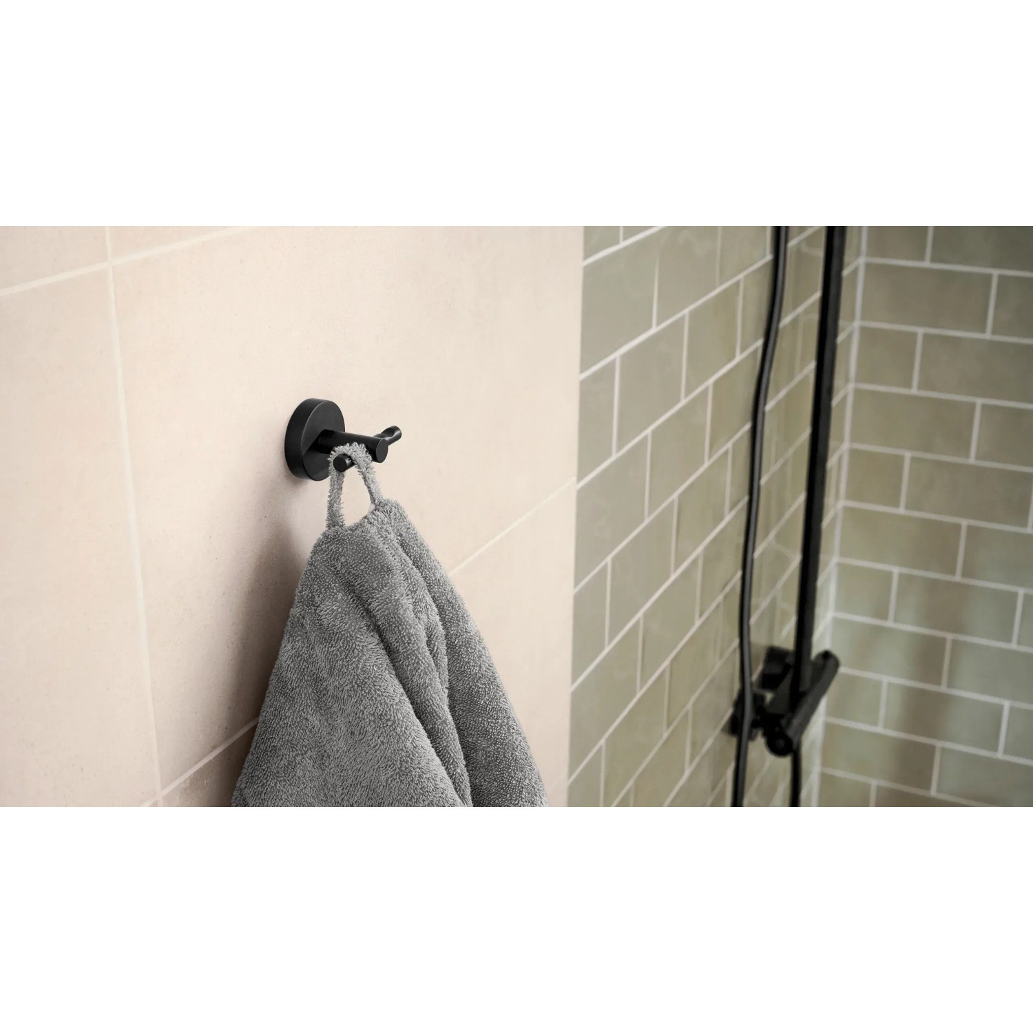 Tesa Moon Bademantelhaken in Graphit mit Handtuch an Wand montiert.