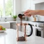 Hand gießt Kaffeepulver in Bodum French Press Kaffeebereiter 1,0l mit Kupferrahmen auf Küchenzeile.