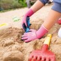 Kind mit pinken Gartenhandschuhen (Größe 4) mit Naturlatex-Beschichtung beim Spielen im Sandkasten.