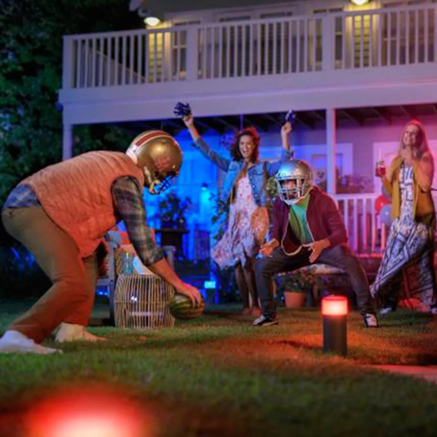 Philips Hue Calla Sockelleuchte in Schwarz im Garten mit feiernden Personen.