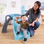 Fröhliches Kleinkind rutscht auf blauer KidKraft Kinderrutsche, Erwachsene hilft. Indoor Spielanlage für Kinder.