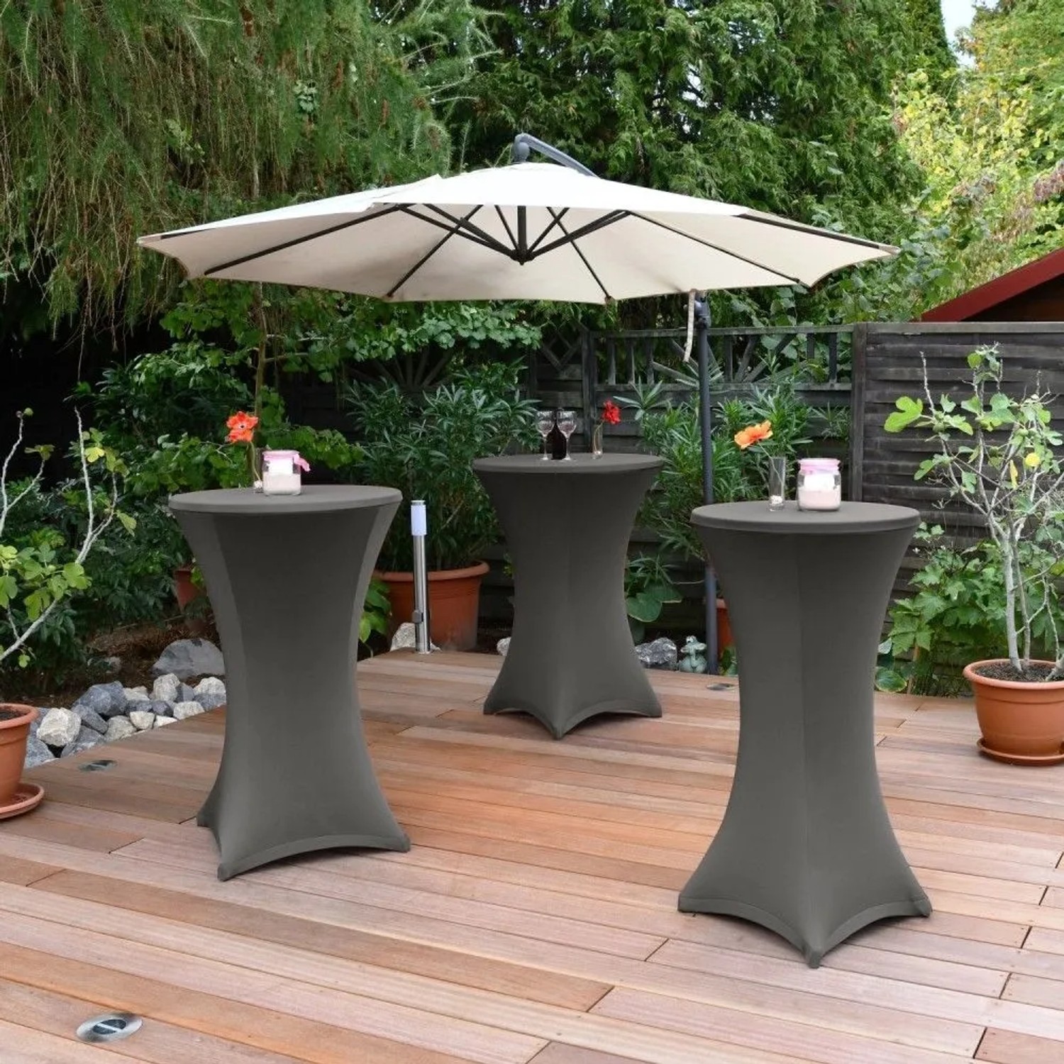 Anthrazitfarbene Beautissu Stella Stehtischhussen auf Holzterrasse, perfekt für Gartenpartys und Events.