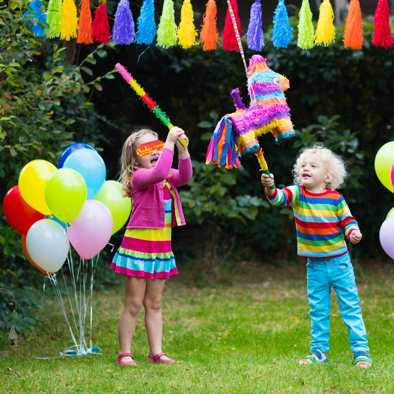 Buntes Pinata Zubehör Set mit Stab und Augenmaske, genutzt von Kindern auf einer Gartenparty. Für Spiel & Spaß.