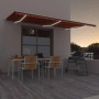 Ausgezogene, orange-braune vidaXL Markise mit LED-Beleuchtung an Hauswand.