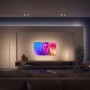 Weiße Philips Hue Gradient Signe Stehleuchte im Wohnzimmer mit Farbverlauf an der Wand.