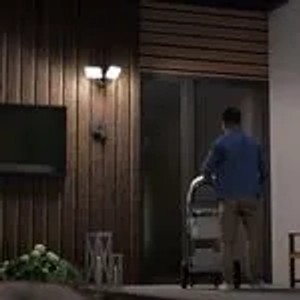 Graue SSC-LUXon LED Außenwandleuchte mit Bewegungsmelder an einer Holzwand.