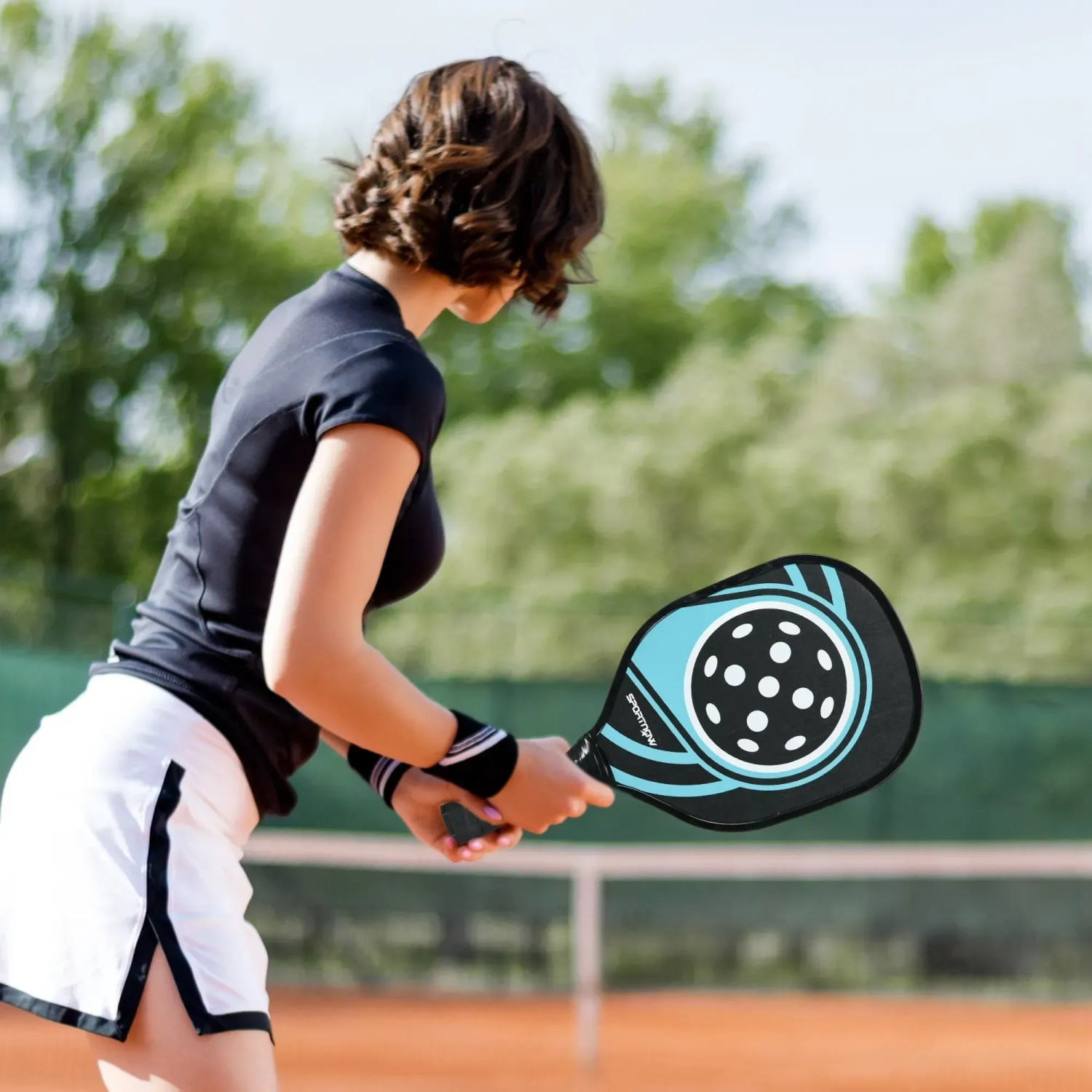 Frau spielt Pickleball mit blau-schwarzem SPORTNOW Schläger.
