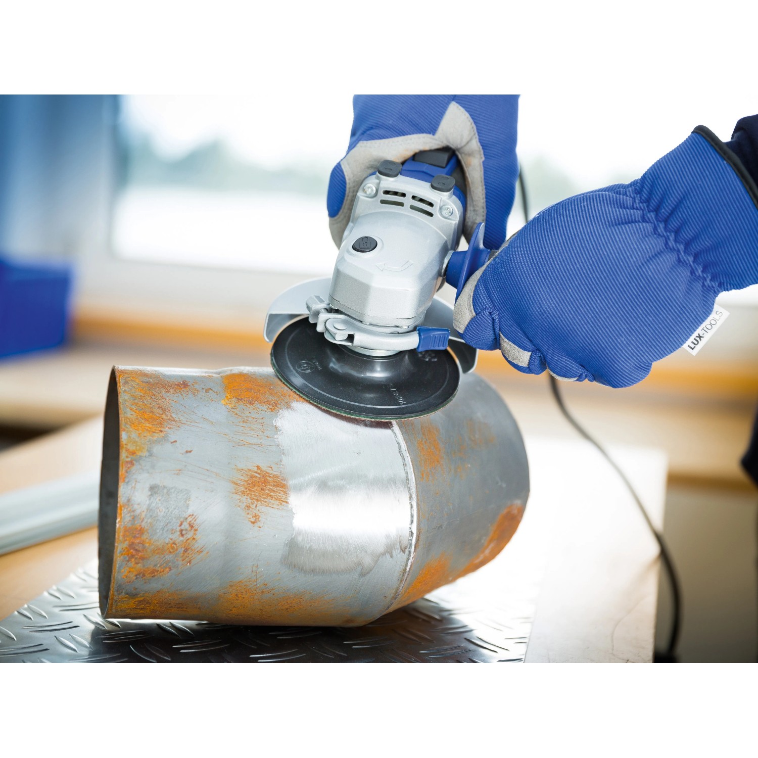 Anwendung einer LUX Fiberscheibe Classic (Körnung 24) auf einem Metallrohr mit einem Winkelschleifer.