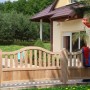 GartenLand Doppeltor Graz aus hellem Lärchenholz mit geschwungener Oberkante im Vorgarten. Robuster Holzzaun für den Eingang.