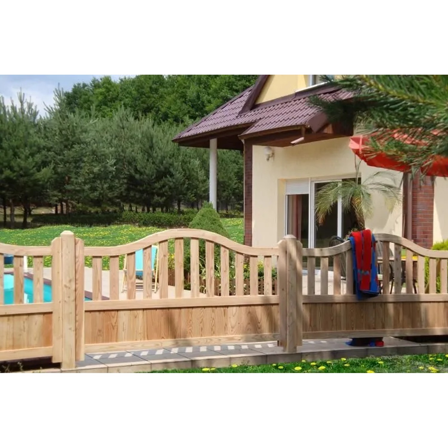 GartenLand Doppeltor Graz aus hellem Lärchenholz mit geschwungener Oberkante im Vorgarten. Robuster Holzzaun für den Eingang.