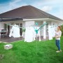 Leifheit Wäscheschirm Linomatic 500 Easy im Garten mit aufgehängter Wäsche und Frau.