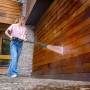 Frau reinigt Holzfassade mit Kärcher Hochdruckreiniger K 7 Comfort Premium eco!Booster.