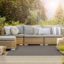 Wetterfester, grauer KARAT Outdoor Teppich Salerno (180x250 cm) auf Terrasse vor Rattansofa.