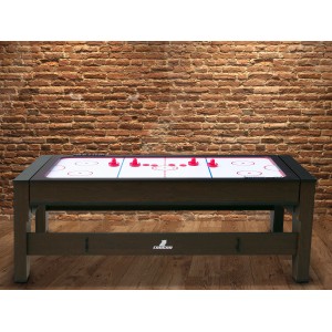 Reverso Spieltisch als Airhockey-Tisch mit roten Pucks vor Backsteinwand.