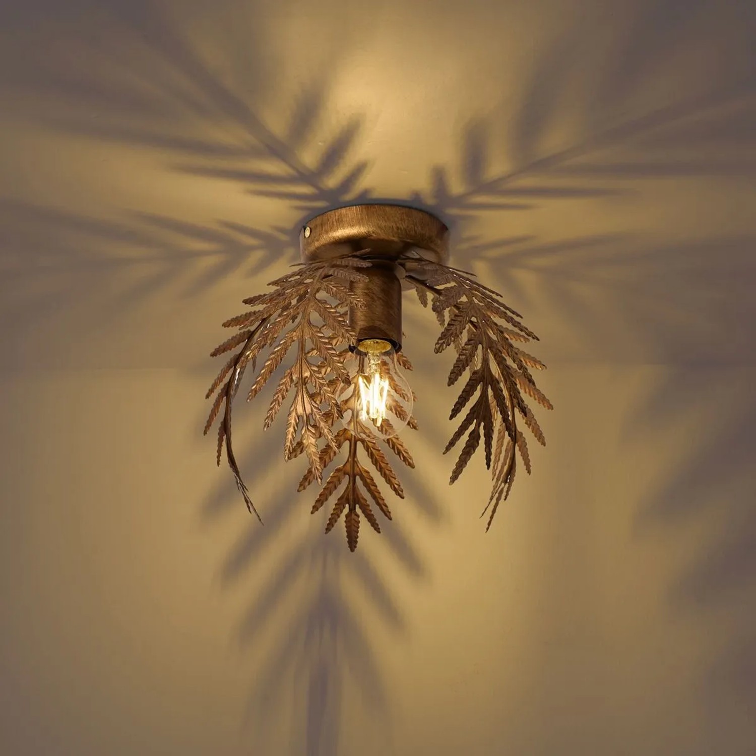 Goldene Vintage Deckenleuchte Botanica mit Blättern und sichtbarer Glühbirne, wirft Schatten an die Decke.