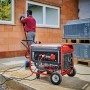 Roter, robuster Einhell Benzin-Stromerzeuger TC-PG 65/E5 auf Rädern versorgt Werkzeug auf Baustelle.