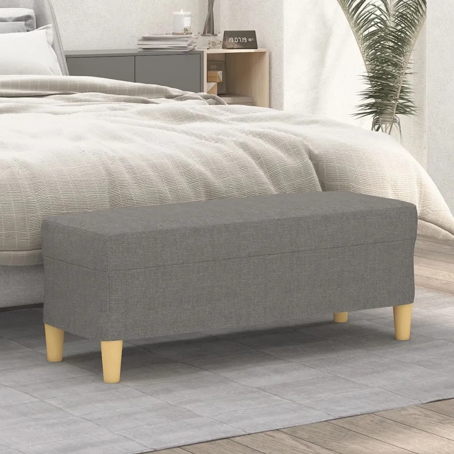 Dunkelgraue gepolsterte Sitzbank aus Stoff mit hellen Holzbeinen im Schlafzimmer. Ideal als Schuhbank oder Bettbank.