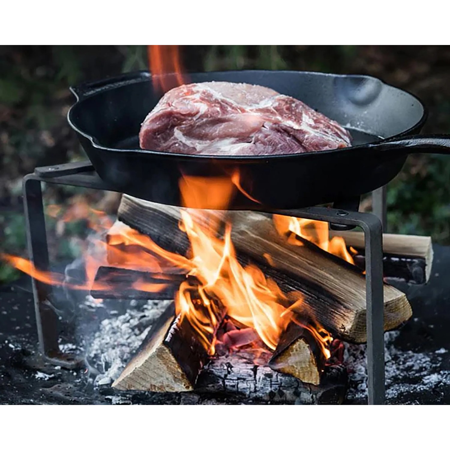 Petromax Feuerpfanne FP30-T: Gusseisenpfanne mit Stiel über offenem Feuer mit Fleisch.